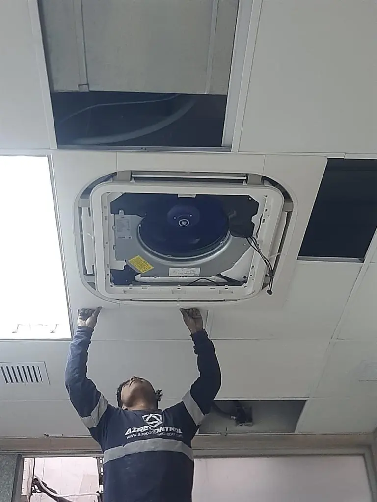 Técnico instalando un equipo de aire acondicionado tipo cassette en un cielo raso